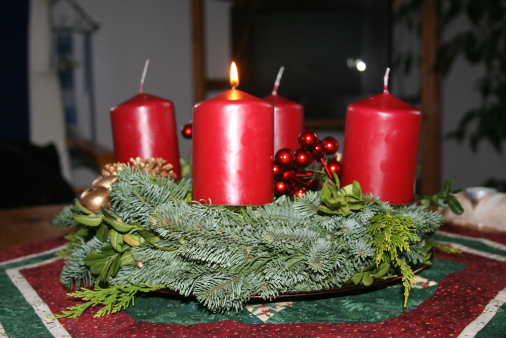Adventskranz mit einer brennenden Kerze